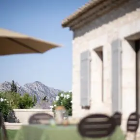 Détail d'une façade en pierre, la chaîne des Alpilles à l'arrière-plan et les Calans à Eygalières