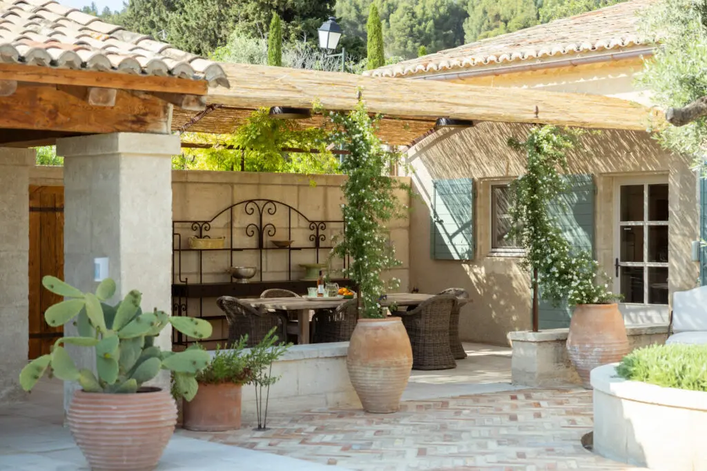 Salon d'extérieur sous la treille, jarres anciennes, jasmins et glycines. Bosc Gardens