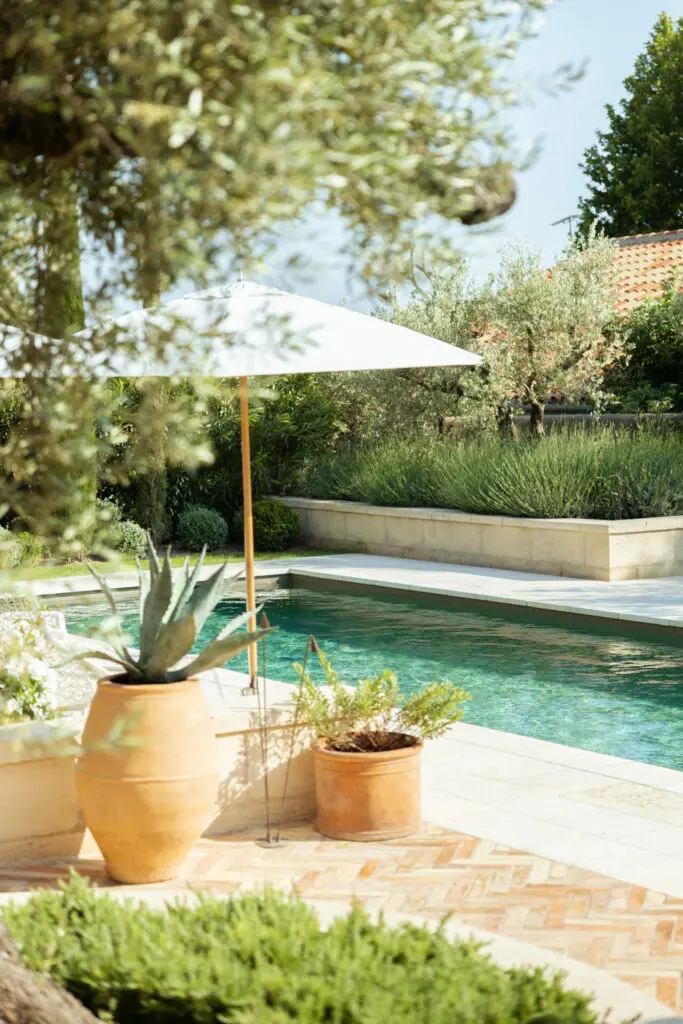 Piscine, parasol et cactées en jarre, banquette de pierre autour du bassin. Bosc Gardens