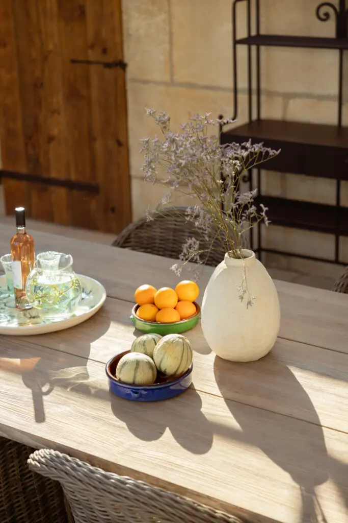 Table en bois, coupe d'oranges et vase dans la lumière rasante