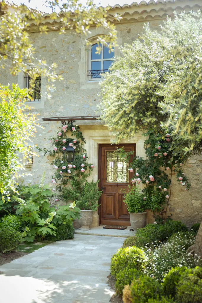 Les rosiers et les pots encadrent la porte d'entrée, la petite marquise sera bientôt recouverte. Bosc Gardens