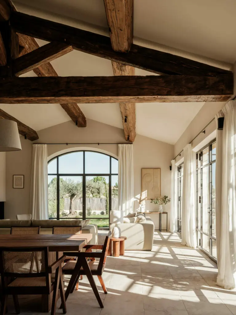 Séjour sous charpente, baie métallique cintrée ouverte sur le jardin