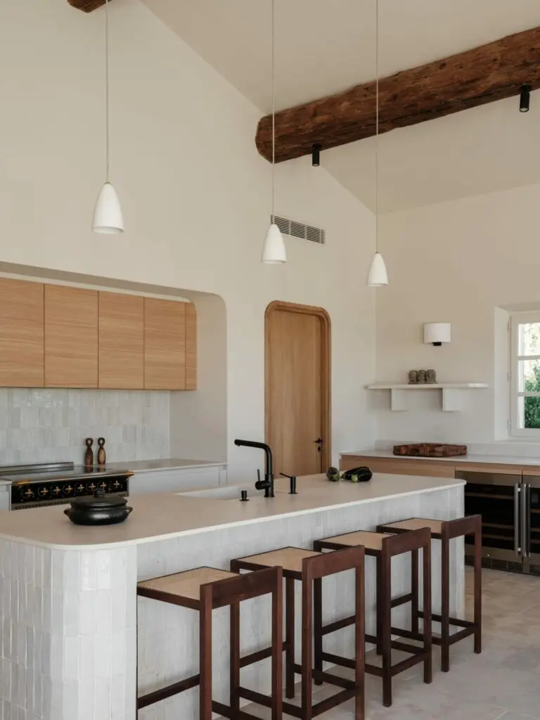 Cuisine sous plafond cathédrale, îlot central en zelliges blancs, rangements en chêne, plan en pierre