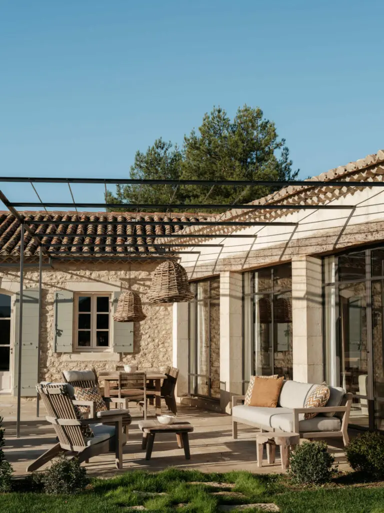 Treille métallique prolongeant la terrasse, façade en pierre, poutres anciennes, poteaux en pierre