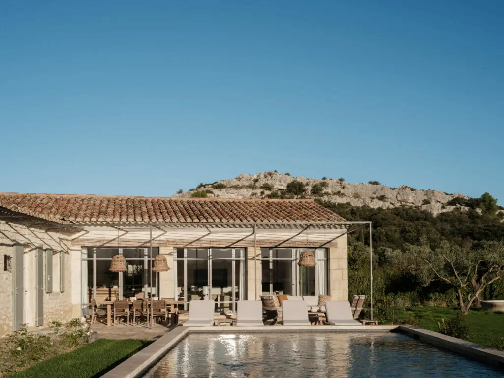La piscine, margelles en pierre, le salon d'été sous la treille, les Alpilles à l'horizon