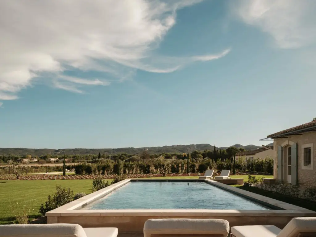 Piscine bordée de pierre, alignement de cyprès et horizon des Alpilles