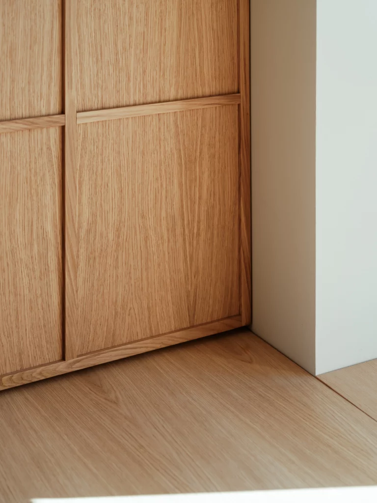 Placards de chêne et parquet de chêne se rejoignent dans l'angle, sous la lumière rasante. Bosc Architectes