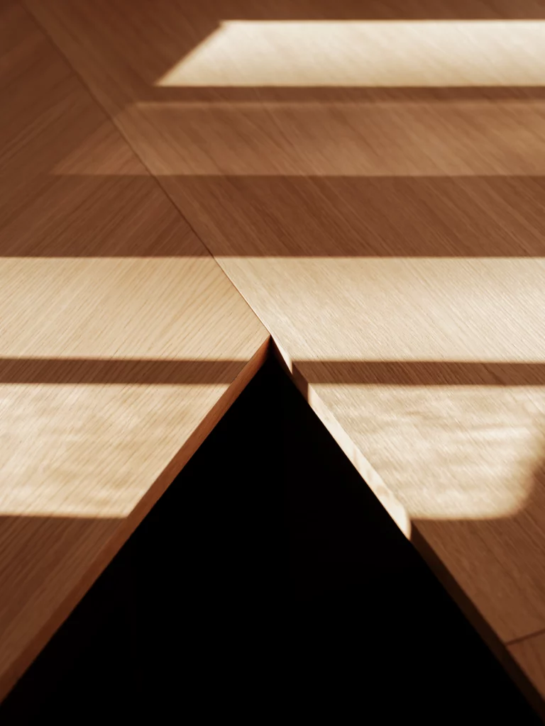 Le soleil découpe des bandes claires sur les bureaux en chêne de l'agence. Bosc Architectes