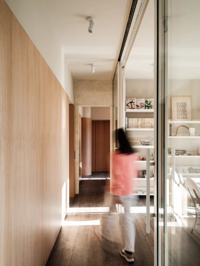 Le couloir de l'agence, lambris de chêne d'un côté, cloison vitrée sur la salle des matières. Bosc Architectes